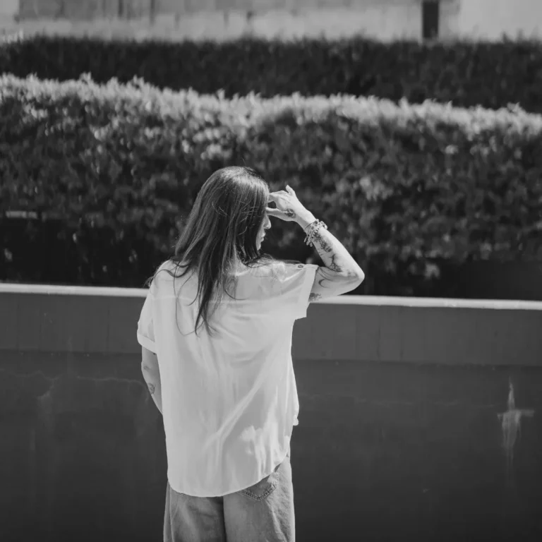 Donna matura osserva la luce oltre una finestra, immagine della poesia Ho imparato a restare di Margherita Roncone.